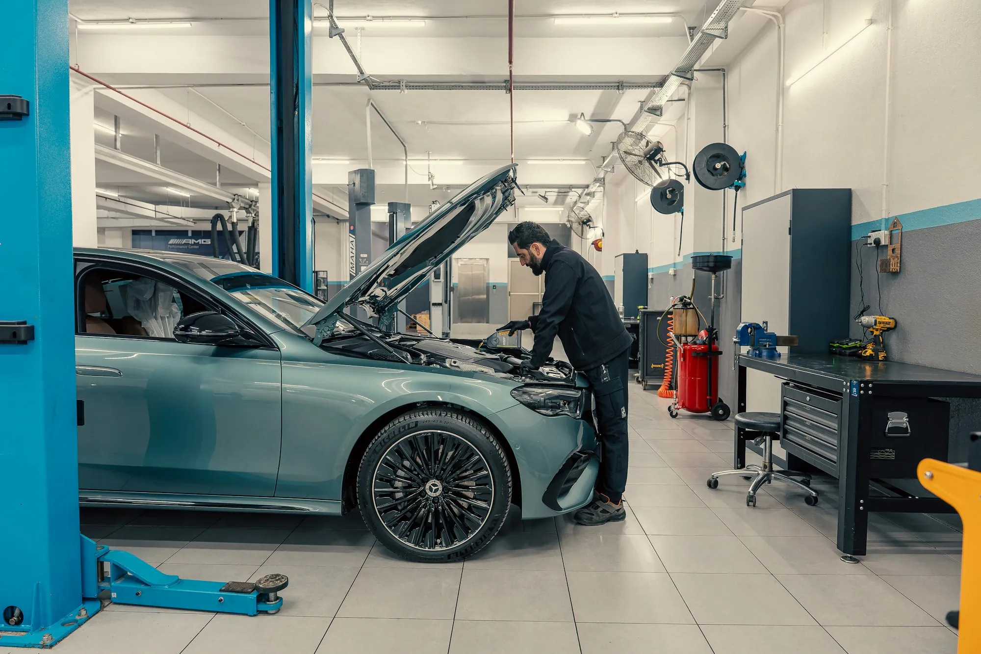 Mechanic leaning into the engine bay of a car in a bright repair shop