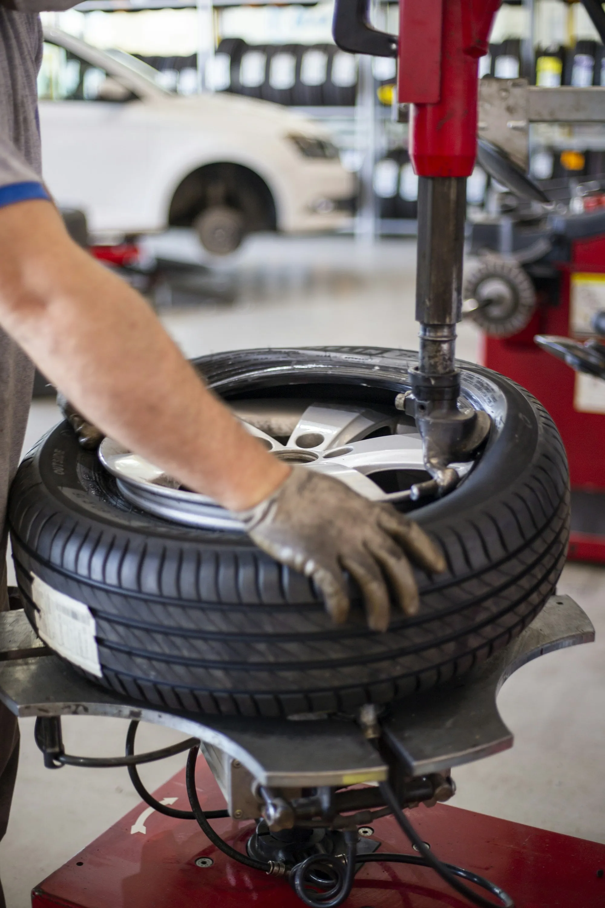 Gloved hands working a tire onto a wheel on a tire machine